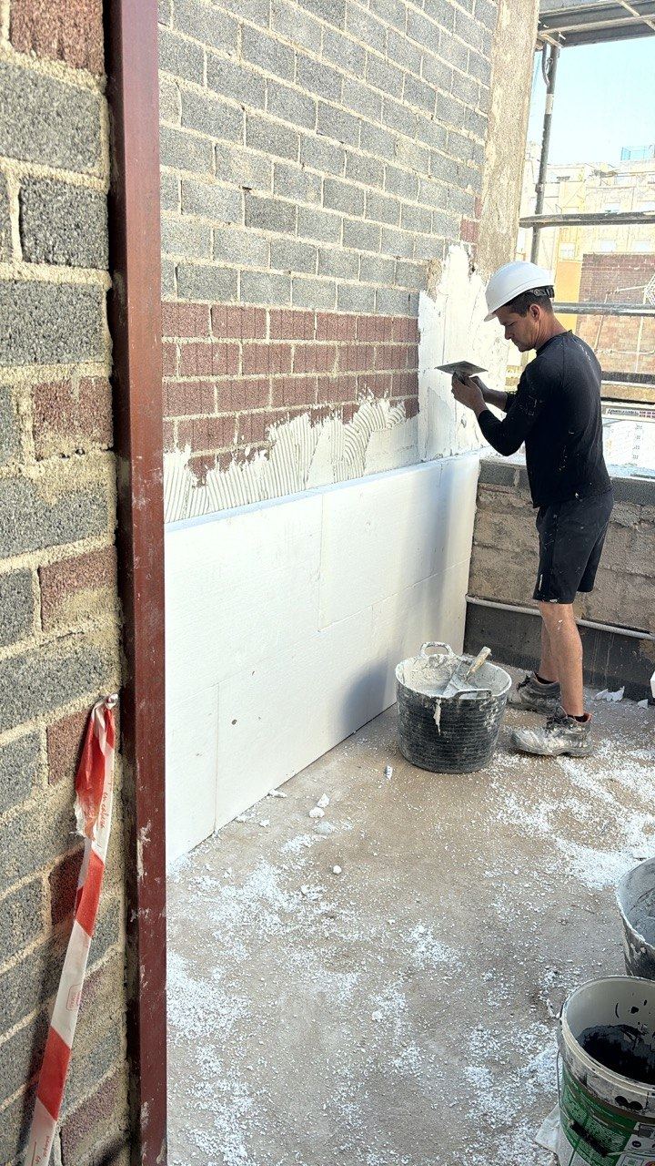 Aplicador trabajando el mortero de regularización en la fachada de una vivienda